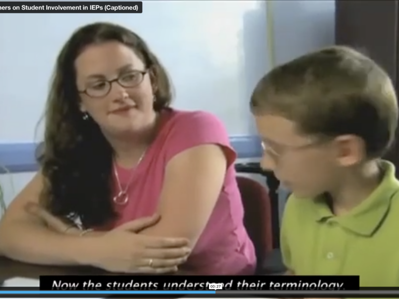 Screen grab from video featuring a teacher sitting with a young student discussion his IEP.