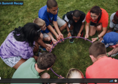 Screen capture from the 2016 Summit Recap video featuring a group of youth squatting in a circle and holding a hula-hoop in their hands.