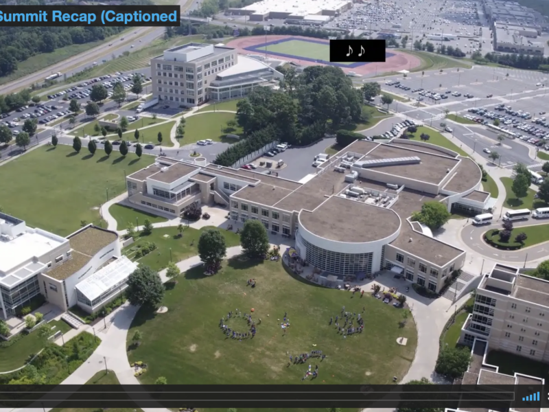 Screen grab from 2017 Summit Recap Video showing an overhead view of the JMU campus where the Summit takes place. Brown-roofed buildings with white sidewalks and green space is visible.