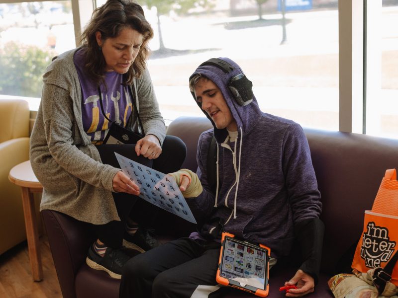 I’m Determined 2019-181 a teacher helps a teenage boy communicate with a letter-board