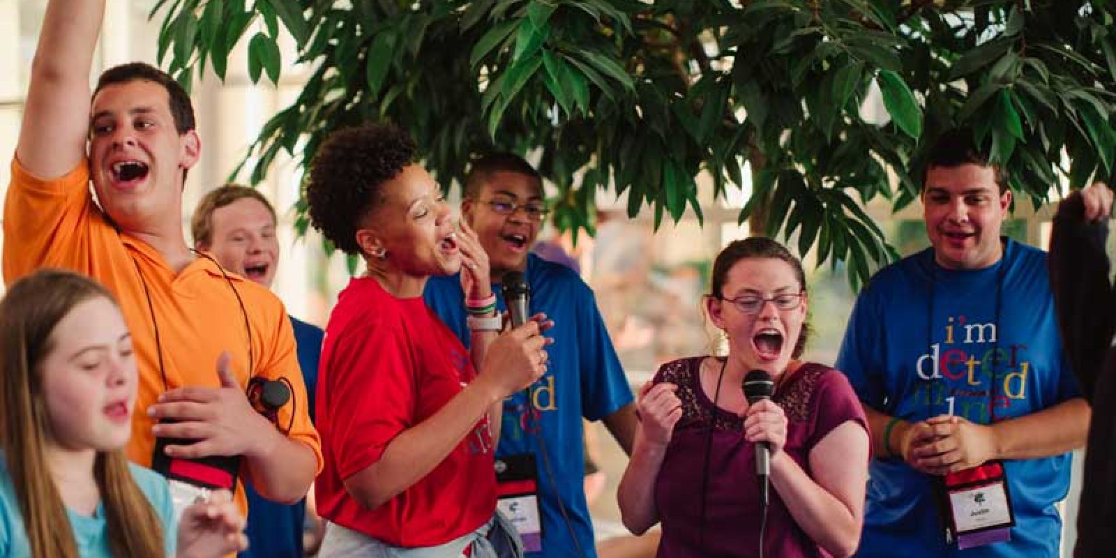 youth leaders in brightly colored shirts sing joyfully into microphones