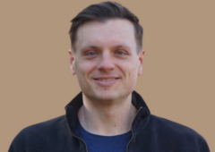 Headshot of Jarrod Hobson, male with short brown hair, wearing a blue shirt and dark jacket