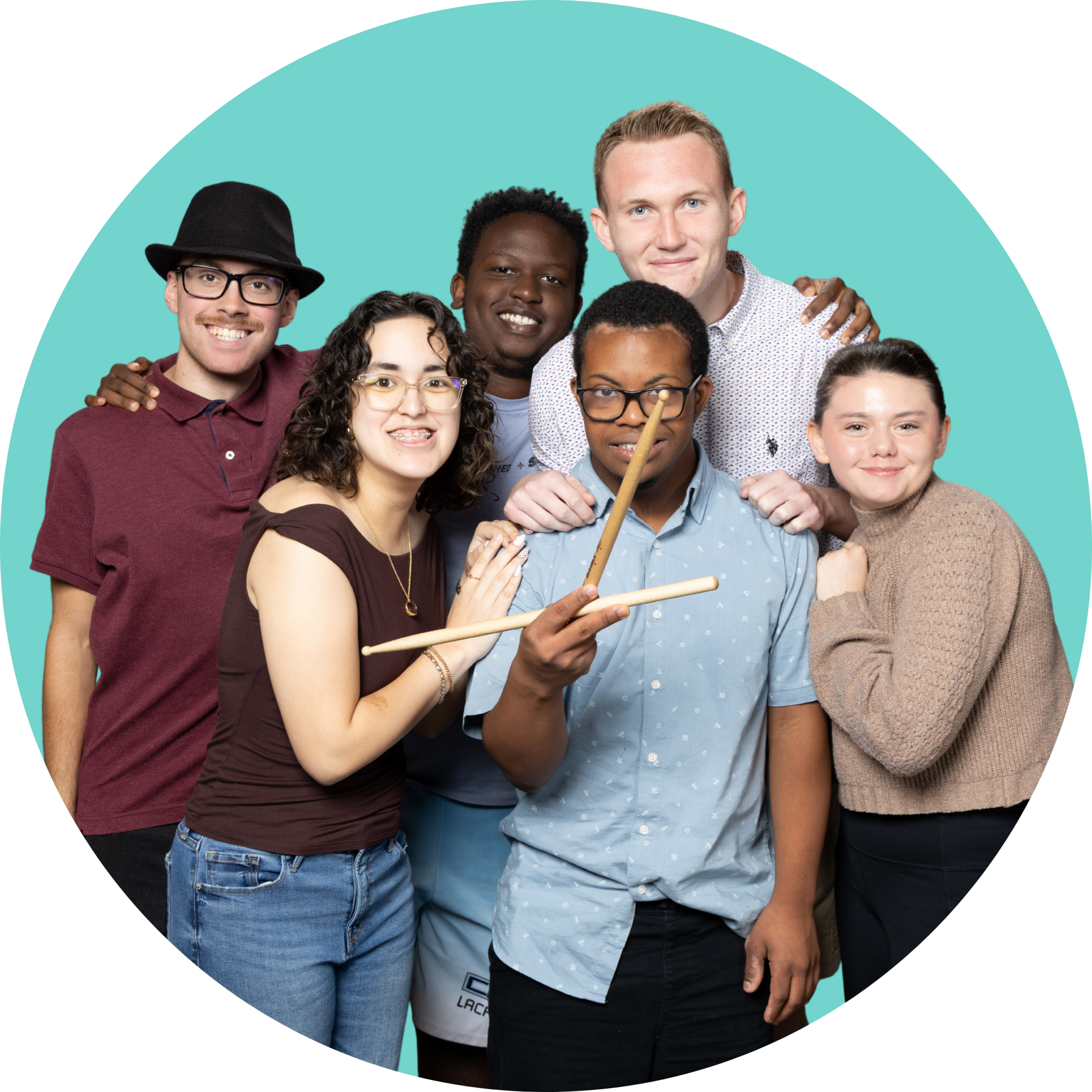 A group of six Youth Leaders with their arms around each other, smiling. One youth leader in the front is holding drum sticks.