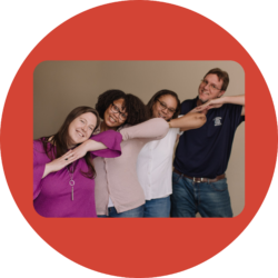 Four I'm Determined staff members pose in an "awkward family photo" style pose where each person has their hands under their chin, elbows out, smiling with heads tilted.