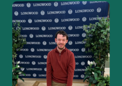 Joseph Jones standing infront of a Longwood University banner.
